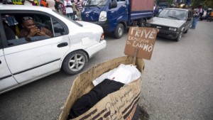 A man takes pictures from a taxi of a fake coffin that represents Provisional President Jocelerme Privert, with a sign that reads Creole “Privert resign or die” in Port-au-Prince.